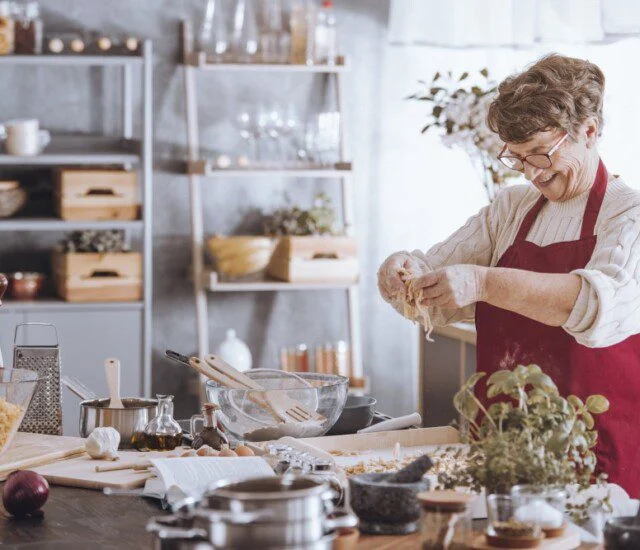 cheerful senior woman in red apron cooks a holiday meal in her contemporary kitchen