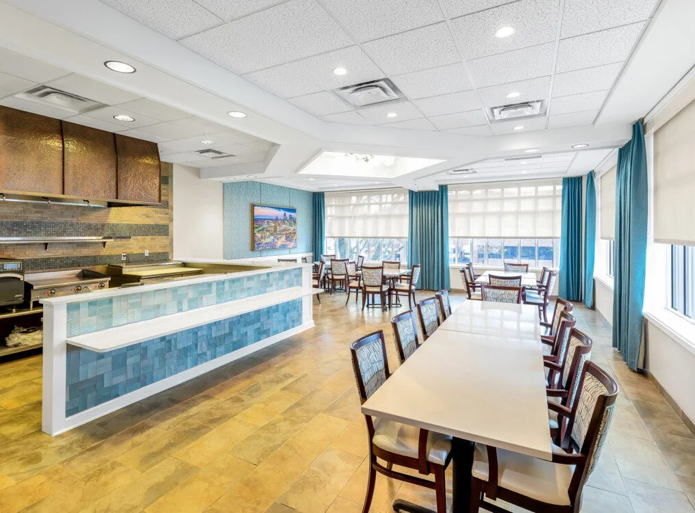 expansive casual dining area with multiple tables and large television at Claridge Court Senior Living Community