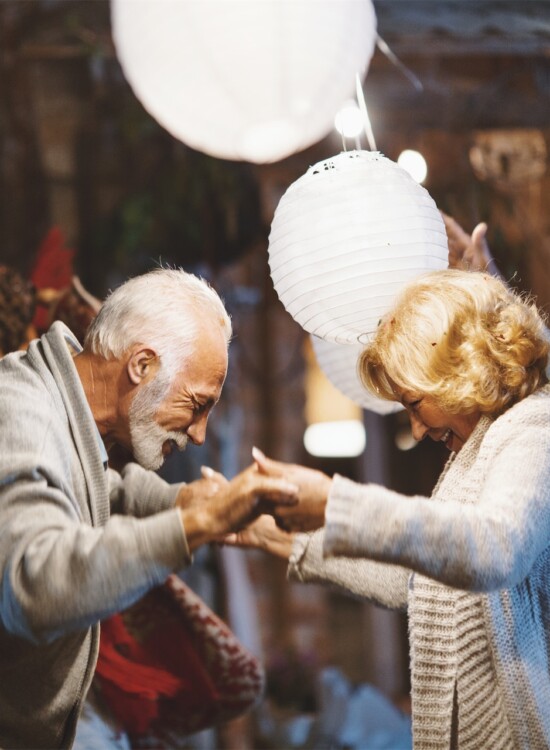 senior couple dances under lanterns while their friends dance and cheer around them