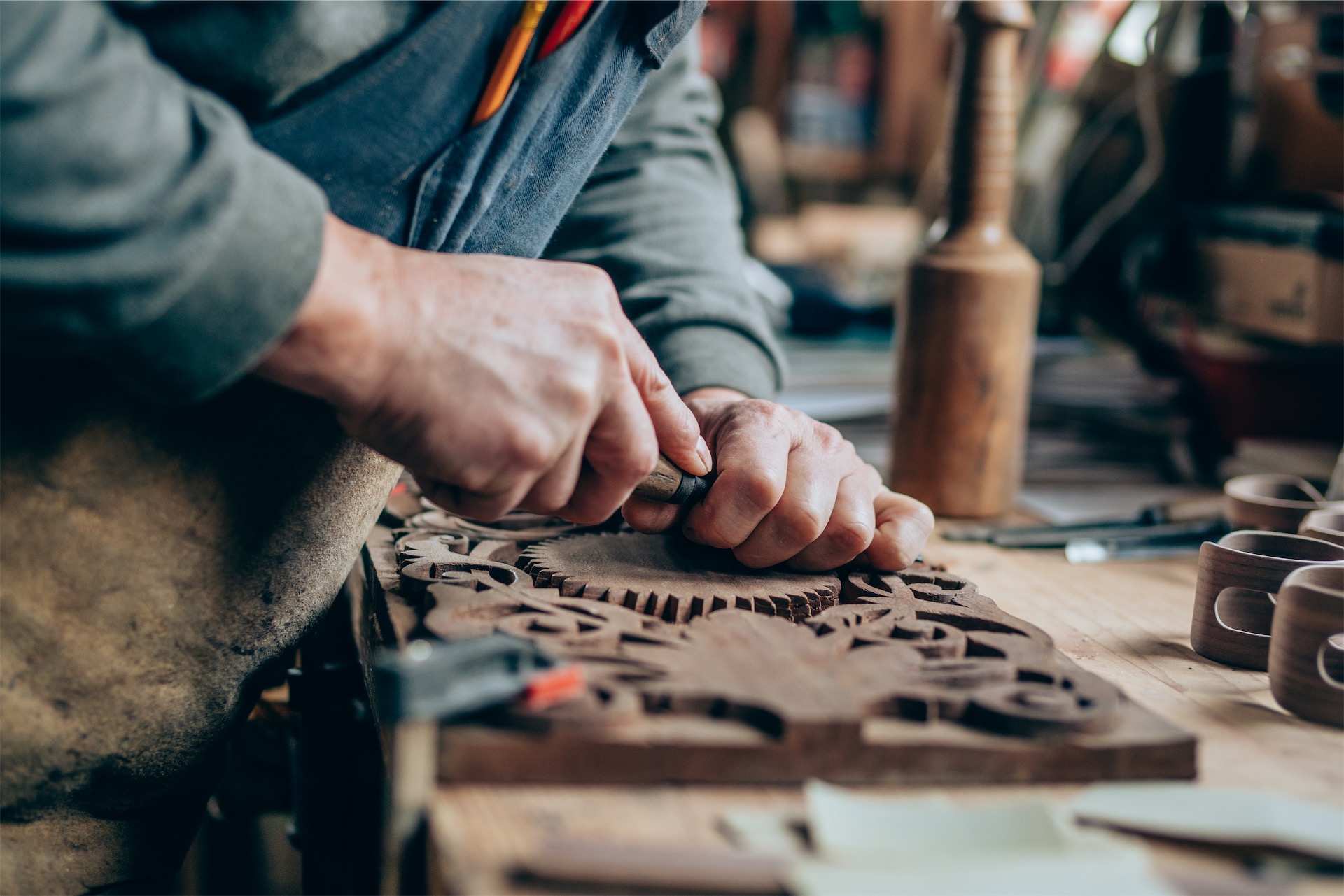 close-up of senior using woodworking tools to carve intricate patterns