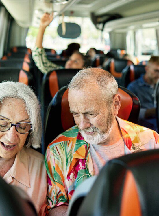 senior couple sits on a bus together heading out for a vacation tour