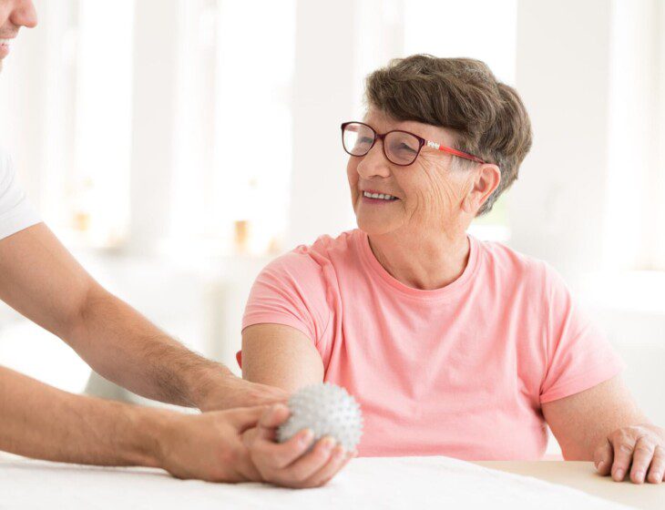 senior woman does physical therapy rehabilitation exercise while seated with the help of a caregiver