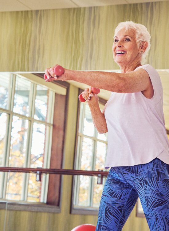 group of seniors smile and lift weights during an aerobics class